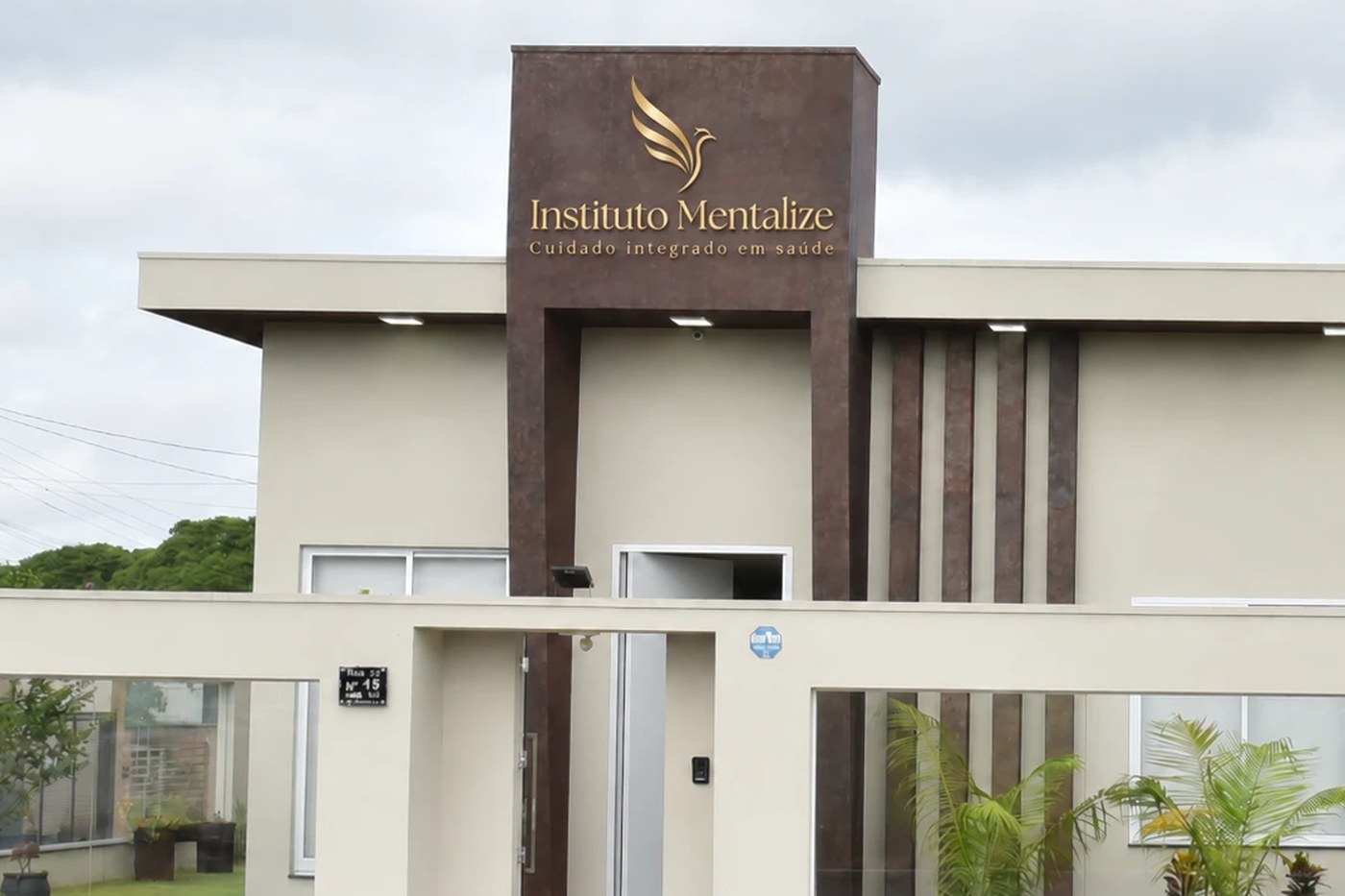 Fachada do Instituto Mentalize em Jataí, com o totem em madeira e o logo em dourado