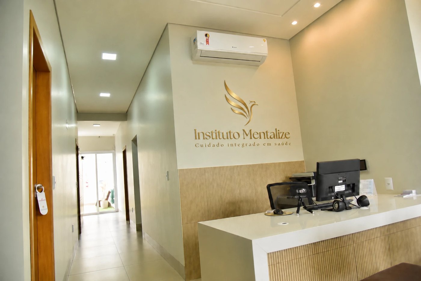 Recepção do Instituto Mentalize, com o logo da clínica em dourado na parede e o corredor ao fundo